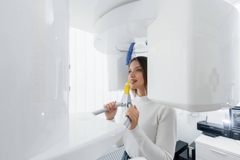 woman using CBCT machine - radiation compliance